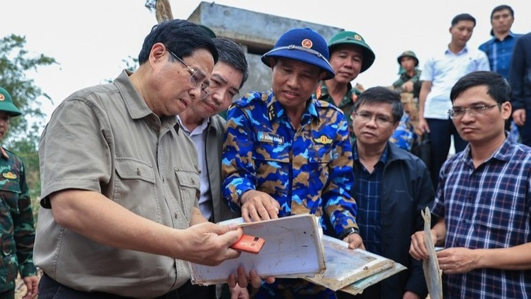 Премьер-министр Фам Минь Тьинь осматривает вещи жителей, которые остались после наводнения. (Фото: VGP)