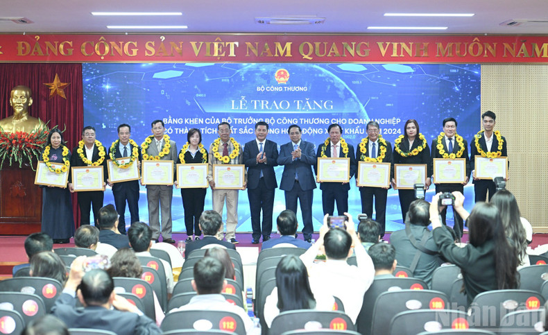 Премьер-министр Фам Минь Тьинь и Министр промышленности и торговли Нгуен Хонг Зиен вручают цветы и награды предприятиям, показавшим выдающиеся результаты.