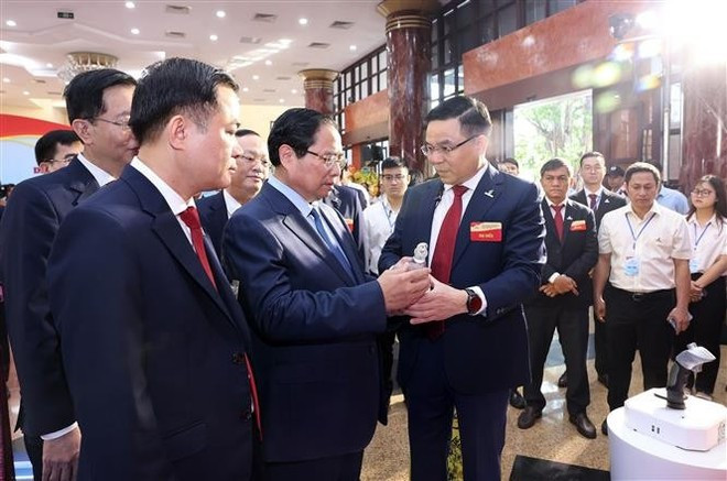 Премьер-министр Фам Минь Тьинь слушает представление типичных продуктов Petrovietnam. (Фото: ВИА) vna-potal-thu-tuong-du-dai-hoi-dang-bo-tap-doan-cong-nghiep-nang-luong-quoc-gia-viet-nam-8187430.jpg
