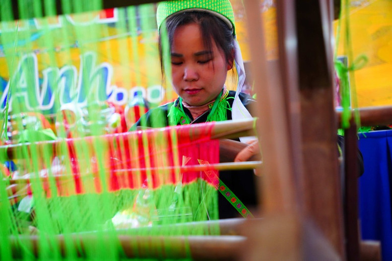 Женщина в национальном костюме народности Нунг демонстрирует традиционную технику ткачества на стенде провинции Лангшон. (Фото: Ты Бить Нгок)