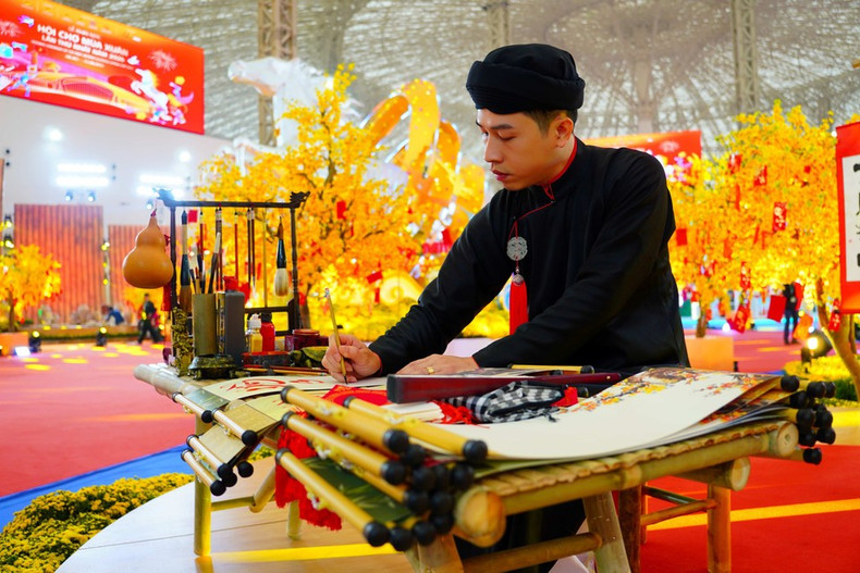 Мастер в традиционном костюме — длинном халате ао тхе и головном уборе кхан сэп — демонстрирует искусство каллиграфии. (Фото: Ты Бить Нгок)