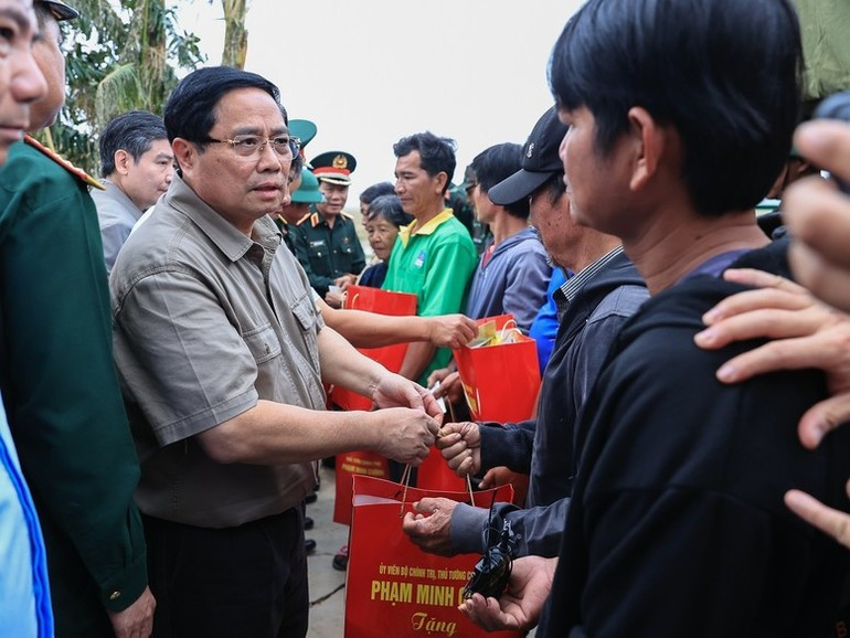 Премьер-министр Фам Минь Тьинь передает помощь жителям деревни Фухыу. (Фото: VGP)