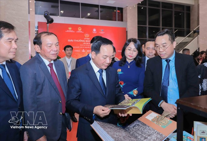 Заведующий Отделом ЦК КПВ по пропаганде, политическому воспитанию и работе с народными массами Чинь Ван Кует вместе с делегатами осматривает экспозицию книг — лауреатов премии. (Фото: ВИА)