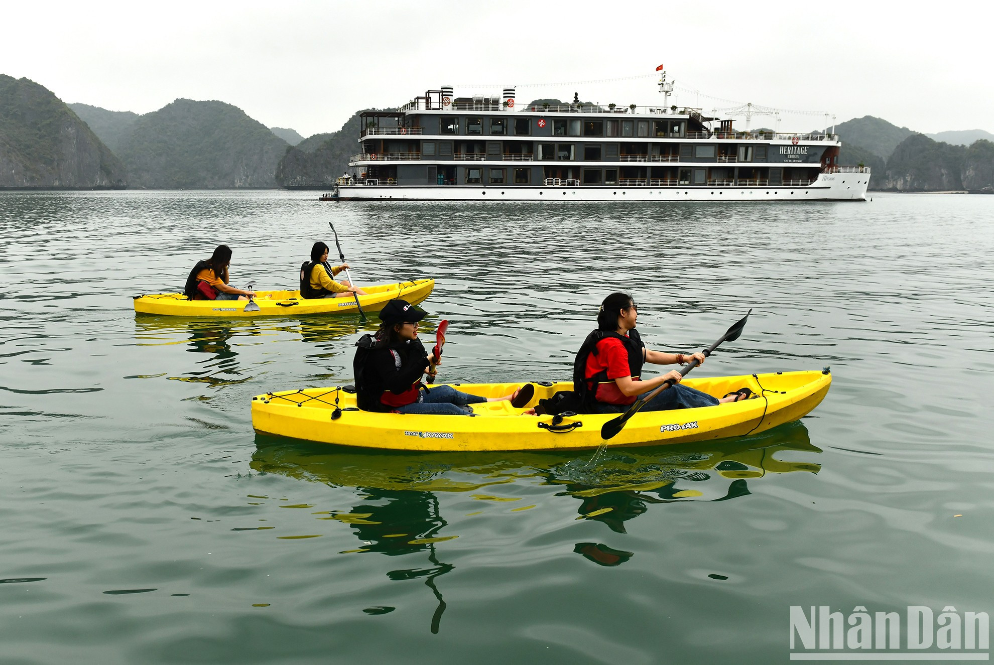 Вьетнамские туристы катаются на байдарке по бухте Ланха. Вьетнамские туристы катаются на байдарке по бухте Ланха.