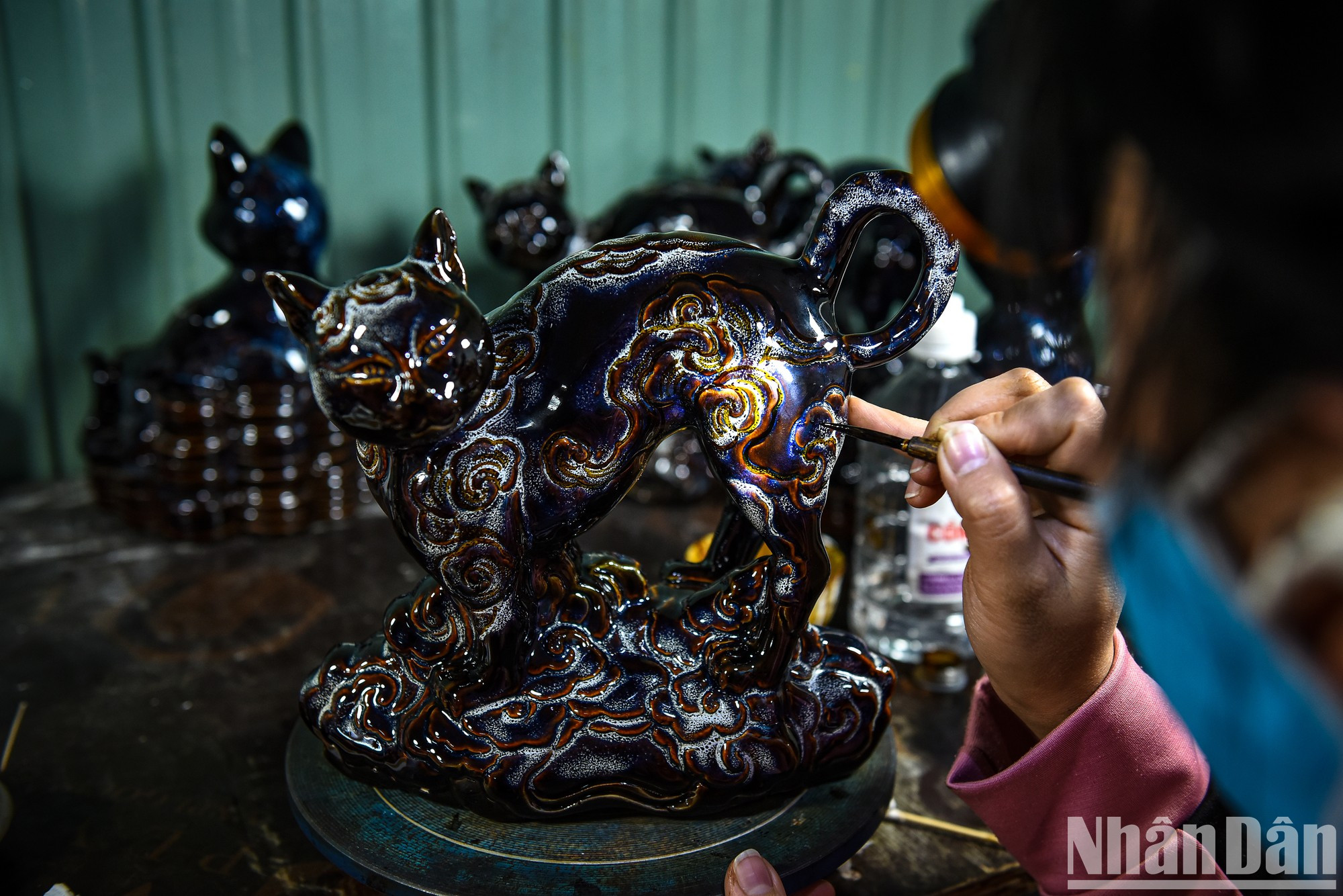 Здесь золотой краской расписывается каждая деталь фигурки кошки. Здесь золотой краской расписывается каждая деталь фигурки кошки.