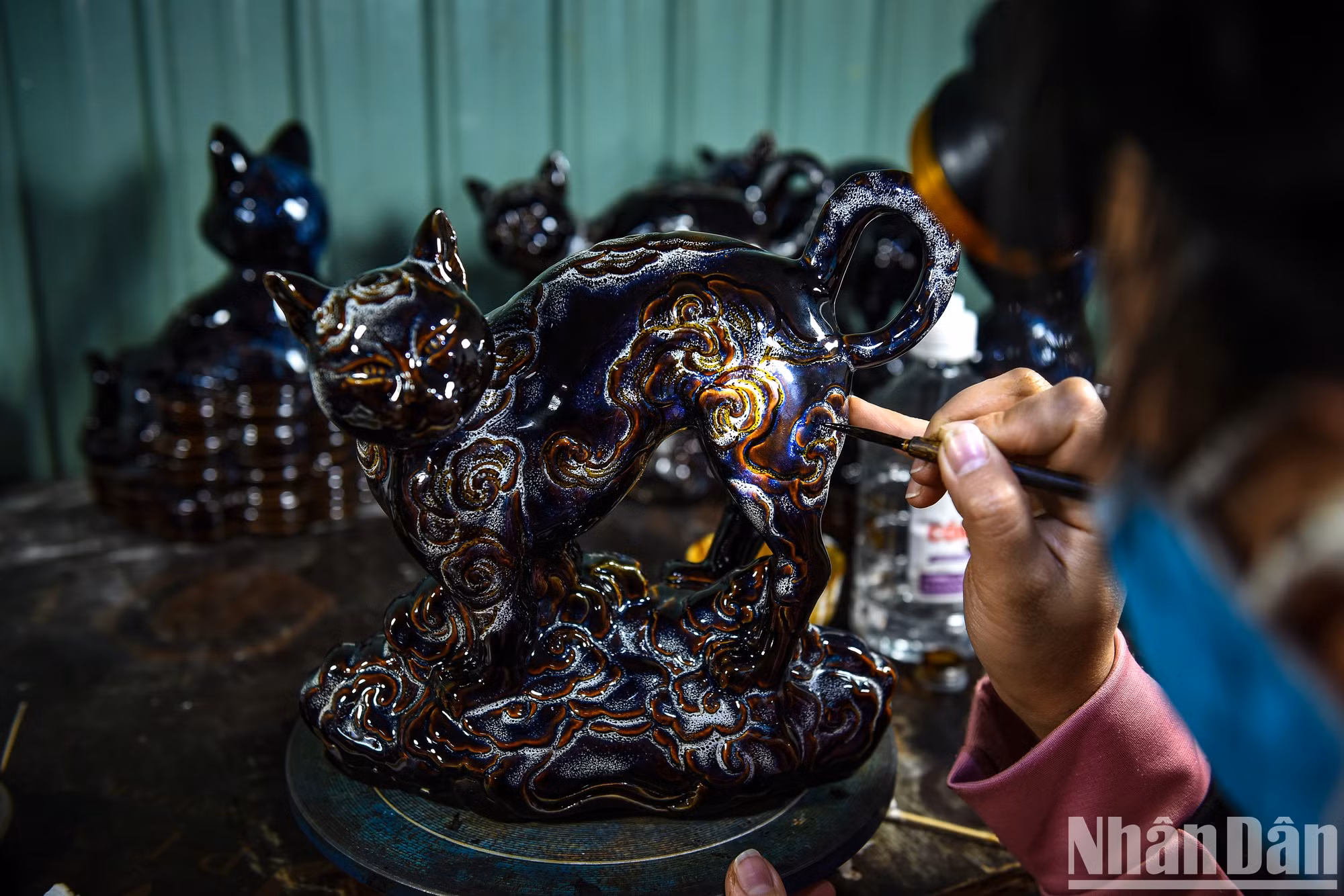 Здесь золотой краской расписывается каждая деталь фигурки кошки.