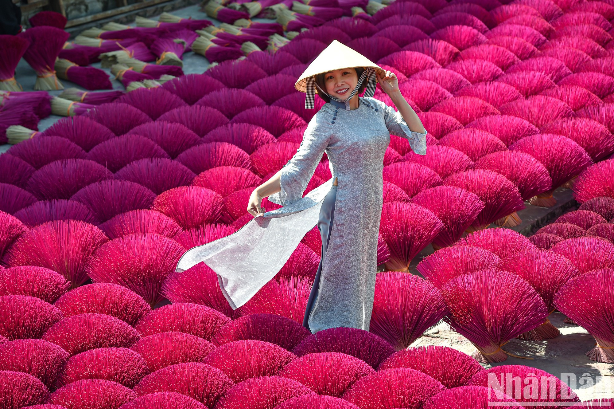 Вьетнамское традиционное платье «аозай» выглядит очаровательно и красиво на фоне пучков красных благовоний.