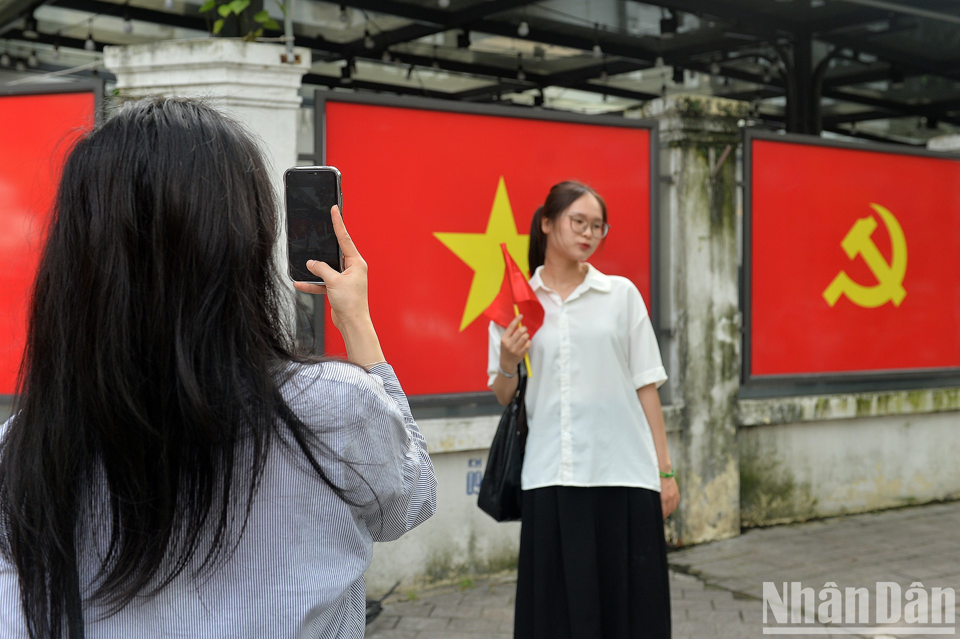 Школьницы столицы фотографируются на фоне государственного флага.