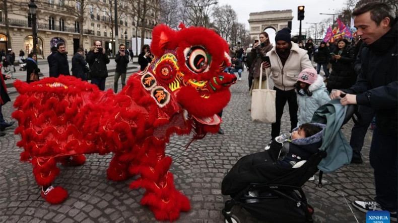 Люди весело наблюдают за представлением танца льва на Елисейских полях в Париже (Франция). Фото: Синьхуа