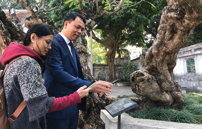 Посетители Храма Литературы сканируют QR-код, прилагаемый к артефакту, для получения подробной информации о нем. Фото: hanoimoi.com.vn