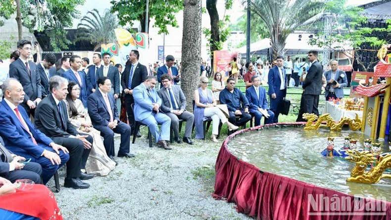 Премьер-министр Фам Минь Тьинь с супругой и делегаты смотрят кукольное представление на воде. Фото: Тхань Жанг