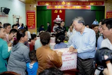 Генеральный секретарь ЦК КПВ То Лам вручает жителям подарки. (Фото: Тху Хюэ)