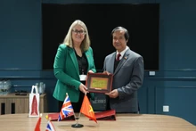 Министр образования и подготовки кадров Нгуен Ким Шон и баронесса Джеки Смит обмениваются памятными подарками. (Фото: ВИА)