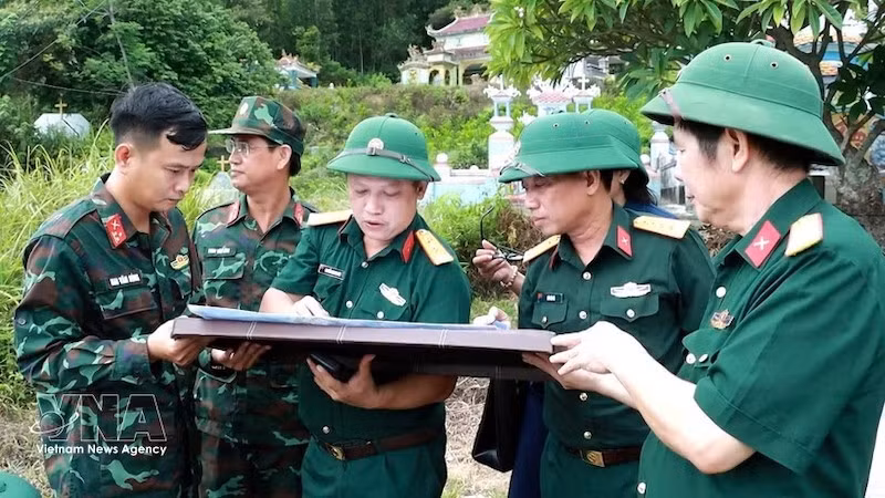Полковник Ха Ван Ай, заместитель политического комиссара Военного командования города Хюэ (третий слева), определяет на карте место захоронения павших военнослужащих. Фото: ВИА