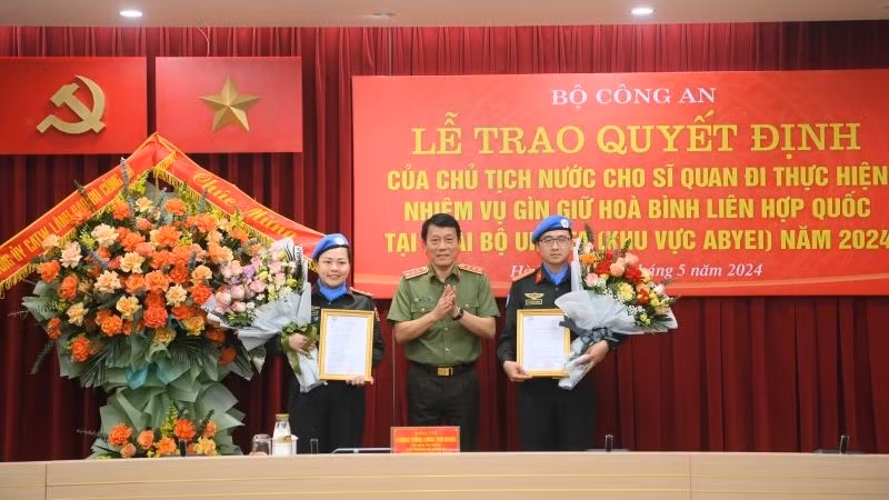 Замминистра общественной безопасности Лыонг Там Куанг вручает вручения решения Президента 2 офицерам.