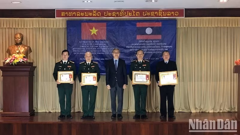 Товарищ Тхонгсаван Фомвихан вручает ордена и медали Лаоса коллективам и частным лицам медицинских учреждений Вьетнама.