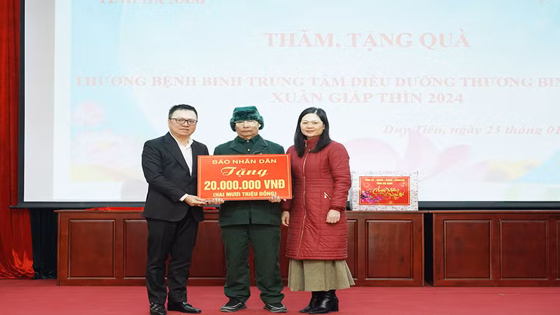 Главный редактор газеты «Нянзан» Ле Куок Минь вручает подарок Центру ухода за инвалидами войны Зюитьен.