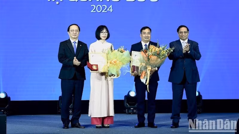 Премьер-министр Фам Минь Тьинь и Министр науки и технологий Хюинь Тхань Дат вручает премию им. Та Куанг Быу ученым. Фото: Чан Хай
