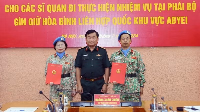 Генерал-полковник Хоанг Суан Тьиен вручает решения двум офицерам.