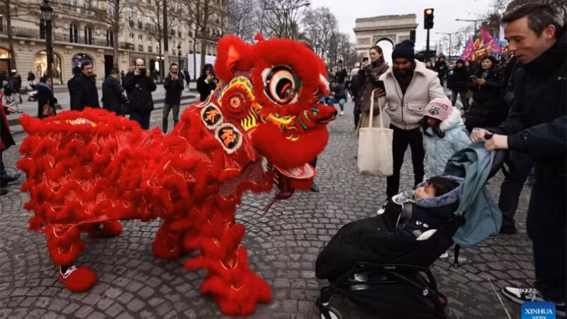 Люди весело наблюдают за представлением танца льва на Елисейских полях в Париже (Франция). Фото: Синьхуа Люди весело наблюдают за представлением танца льва на Елисейских полях в Париже (Франция). Фото: Синьхуа