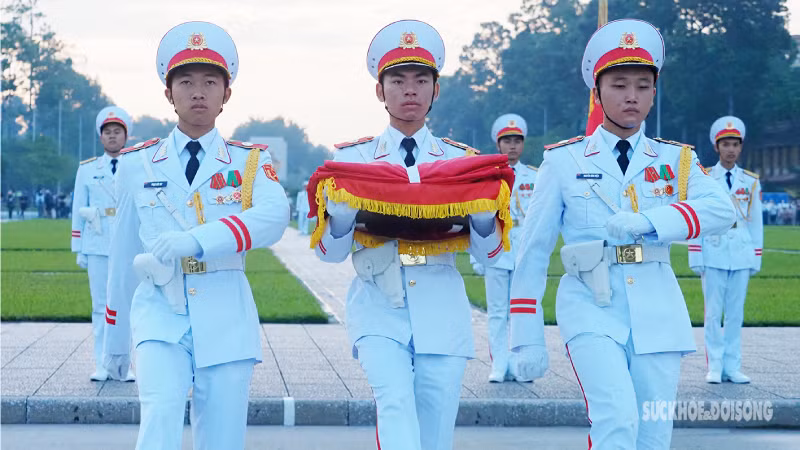 Знаменщик и его ассистент прибывают к установленному месту подъема флага. Солдаты с Государственным флагом подходят к флагштоку.