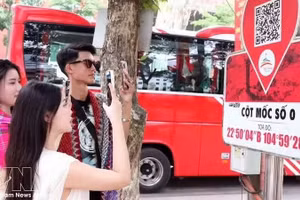 Туристы сканируют QR-коды у отметки Km0 в Хазянге, чтобы получить туристическую информацию. Фото: ВИА