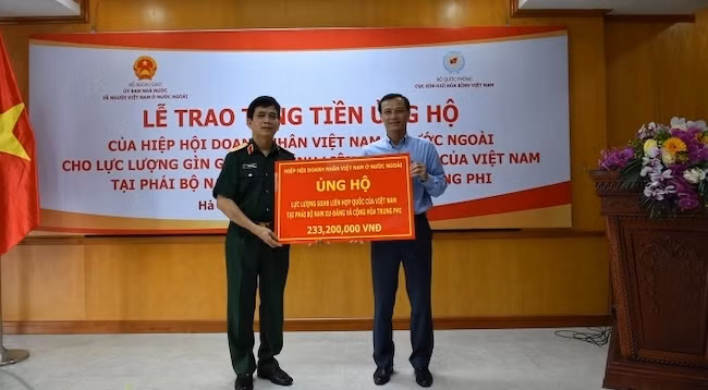 Зампредседателя Государственного комитета по делам вьетнамцев, проживающих за границей, передает главе Управления по поддержанию мира подарок от Общества вьетнамских предпринимателей за рубежом. Фото: baoquocte.vn 