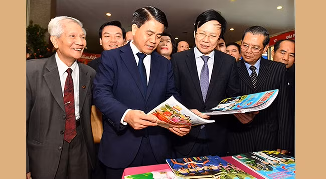 Председатель Народного комитета г. Ханоя Нгуен Дык Тюнг и Постоянный зампредседателя Союза журналистов Вьетнама Хо Куанг Лой вместе с делегатами посещают стенд газеты «Нянзан» на фестивале. Фото: Данг Ань