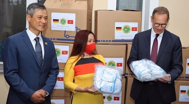 Председатель благотворительной ассоциации «Золотой лотос» Зыонг Тхи Бить Нгок (в центре) от имени ассоциации дарит маску мэру Берлина Михаэлю Мюллеру. Фото: VNA 