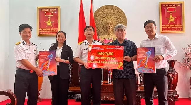 Представители газеты «Нянзан» и Южной электроэнергетической корпорации Вьетнама вручают весенние издания «Нянзан» 125-й бригаде.