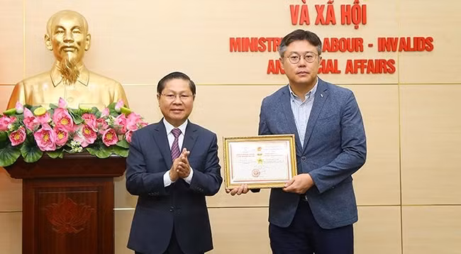 Заместитель министра труда, инвалидов войны и социального обеспечения Ле Тан Зунг вручает памятную медаль г-ну Канг Бюнг Джу.