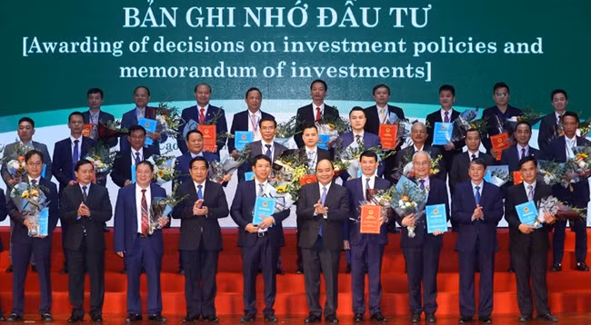 Премьер-министр Нгуен Суан Фук и представители предприятий, получивших инвестиционные сертификаты и подписавших меморандумы о сотрудничестве. Фото: hanoimoi.com.vn