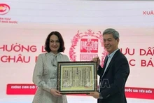 Директор Государственного управления делопроизводства и архивов Данг Тхань Тунг вручает госпоже Елене Бездетко, супруге Посла России во Вьетнаме, оттиск с ксилографической доски с государственным наименованием Вьетнама. Фото: ВИА