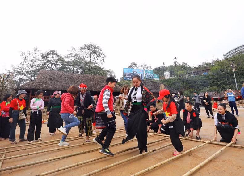 Туристы участвуют в танце с бамбуковыми стволами.