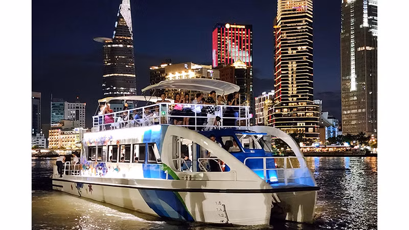 Двухэтажный речной автобус идет по реке Сайгон ночью.